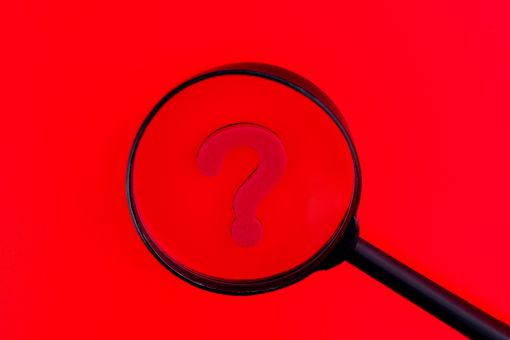 赤い背景の前にある黒い虫眼鏡とハテナマーク