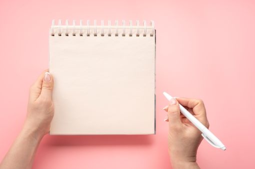 メモとペンを持つ女性の手